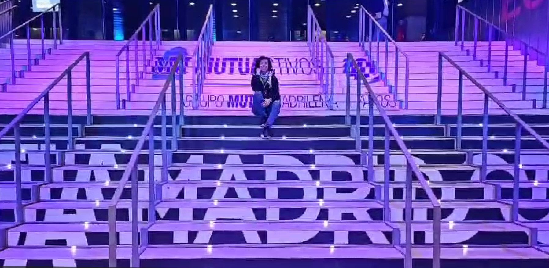 Captura de pantalla 2025-05-01 130904 Carolina Gómez de Virtualia sentada en las escaleras iluminadas de la Caja Mágica