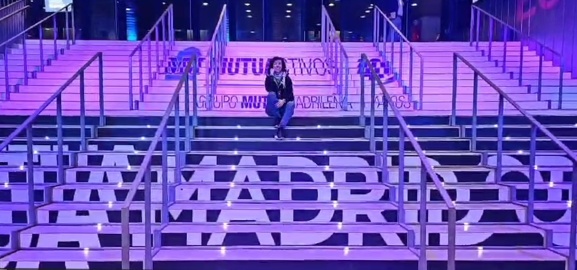 Carolina Gómez de Virtualia sentada en las escaleras iluminadas de la Caja Mágica